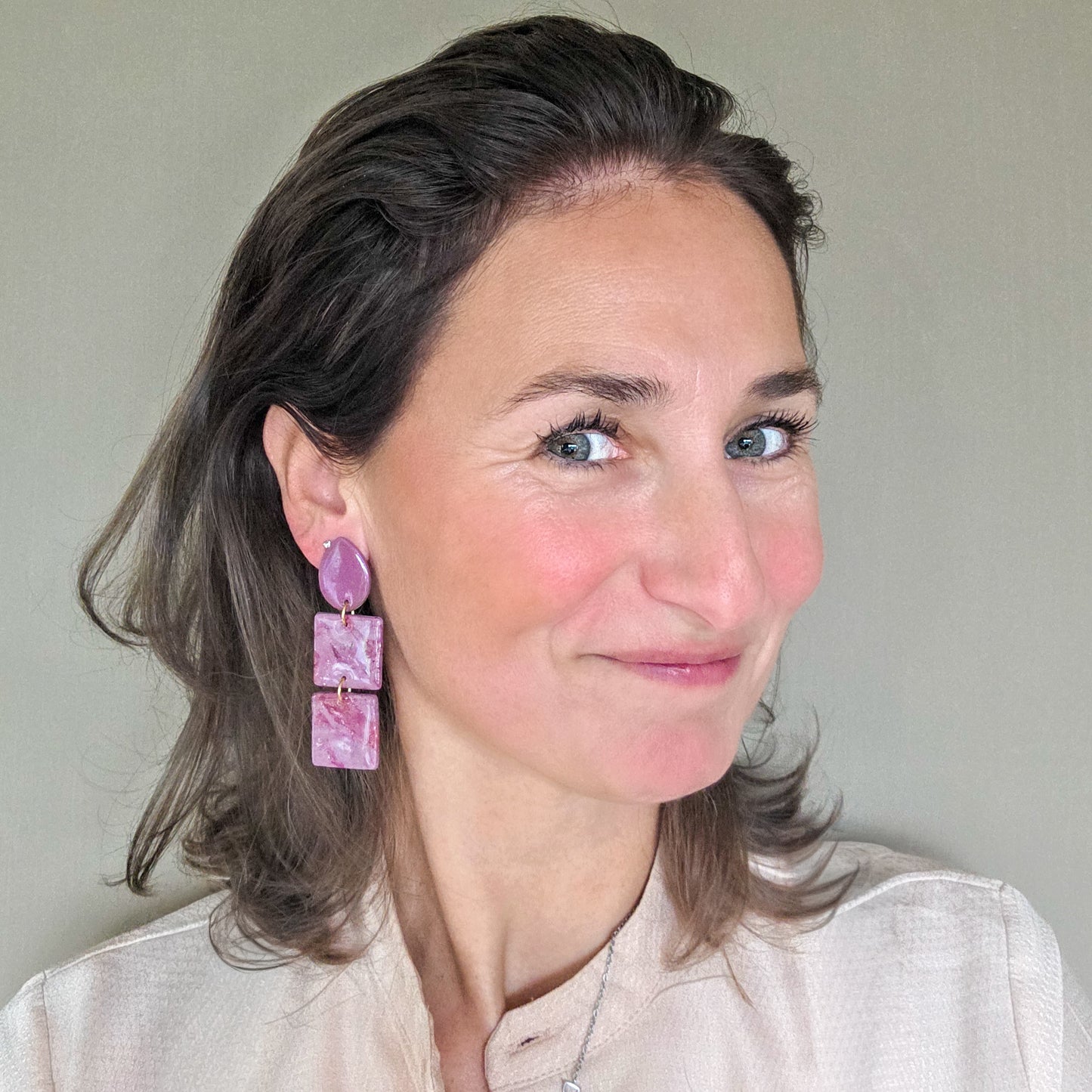 vrouw draagt roze statement oorbellen met druppelvormig oorknopje