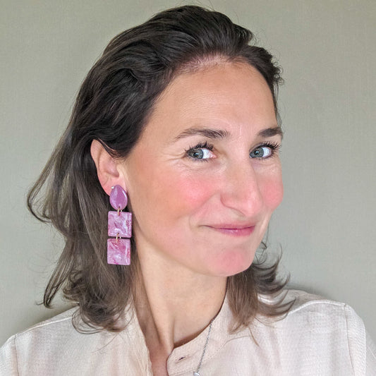 vrouw draagt roze statement oorbellen met druppelvormig oorknopje