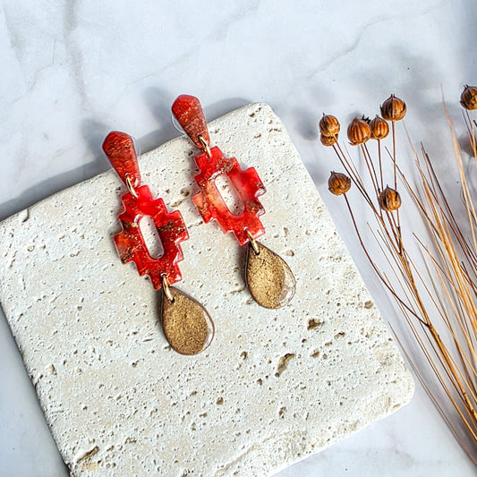 Lange steenrode oorbel met bronskleurige druppel