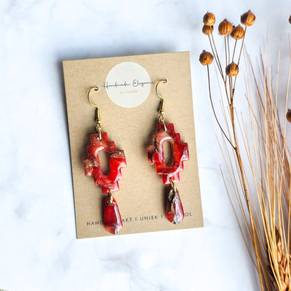 Warm rode lange oorbel met gouden accenten