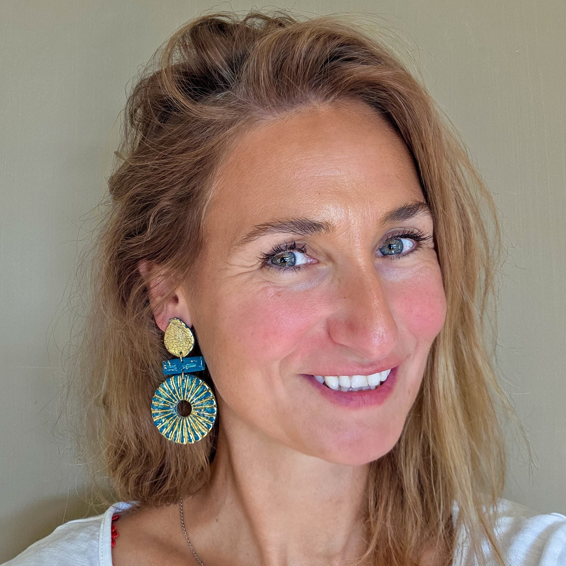 Handgemaakte lange ronde oorbellen met goud en petrol, gedragen aan het oor – Handmade Elegance by Delfine