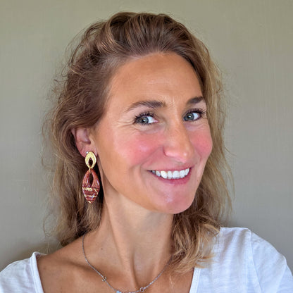 Handgemaakte hoekige steenrode oorbellen met goud, gedragen aan het oor – Handmade Elegance by Delfine