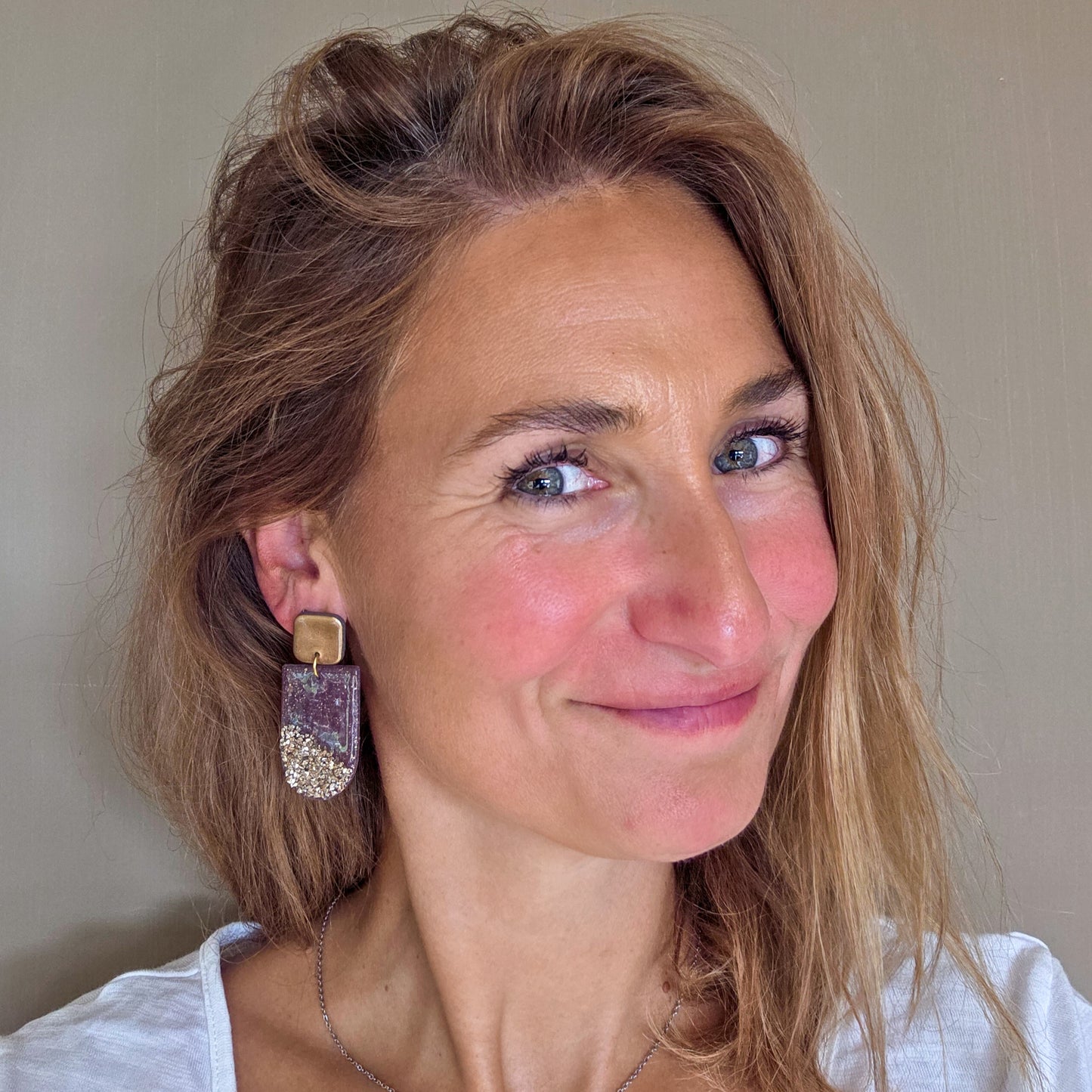 Handgemaakte lange oorbellen in paars taupe met brons, gedragen aan het oor – Handmade Elegance by Delfine