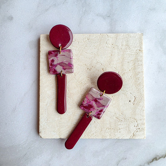 lange burgundy red oorbellen op wit grijs marmeren blad met crème kleurig tegeltje