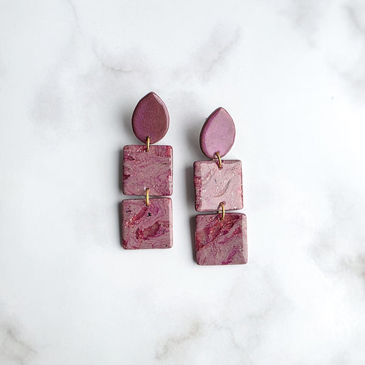 lange roze statement oorbellen met goud spikkel op wit grijs marmeren blad