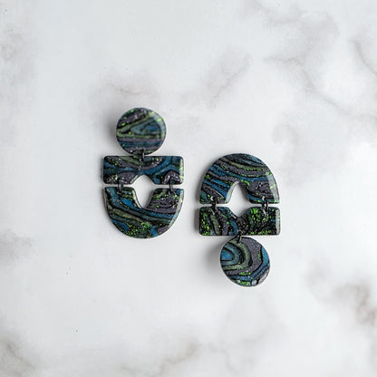 statement oorbellen met groen, zwart en grijs en groene metallic spikkels op wit grijs marmeren blad