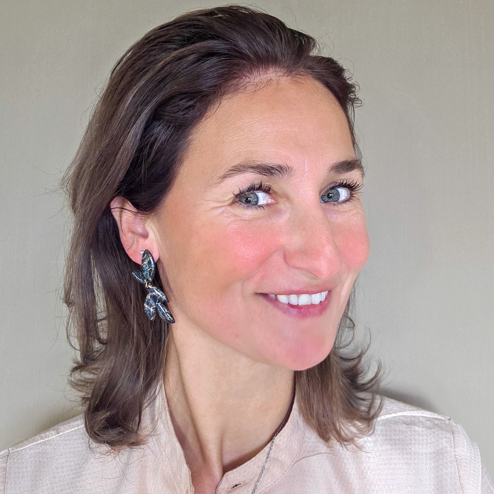 vrouw draagt lange marmer zwarte oorbellen in bladvorm met goudspikkel