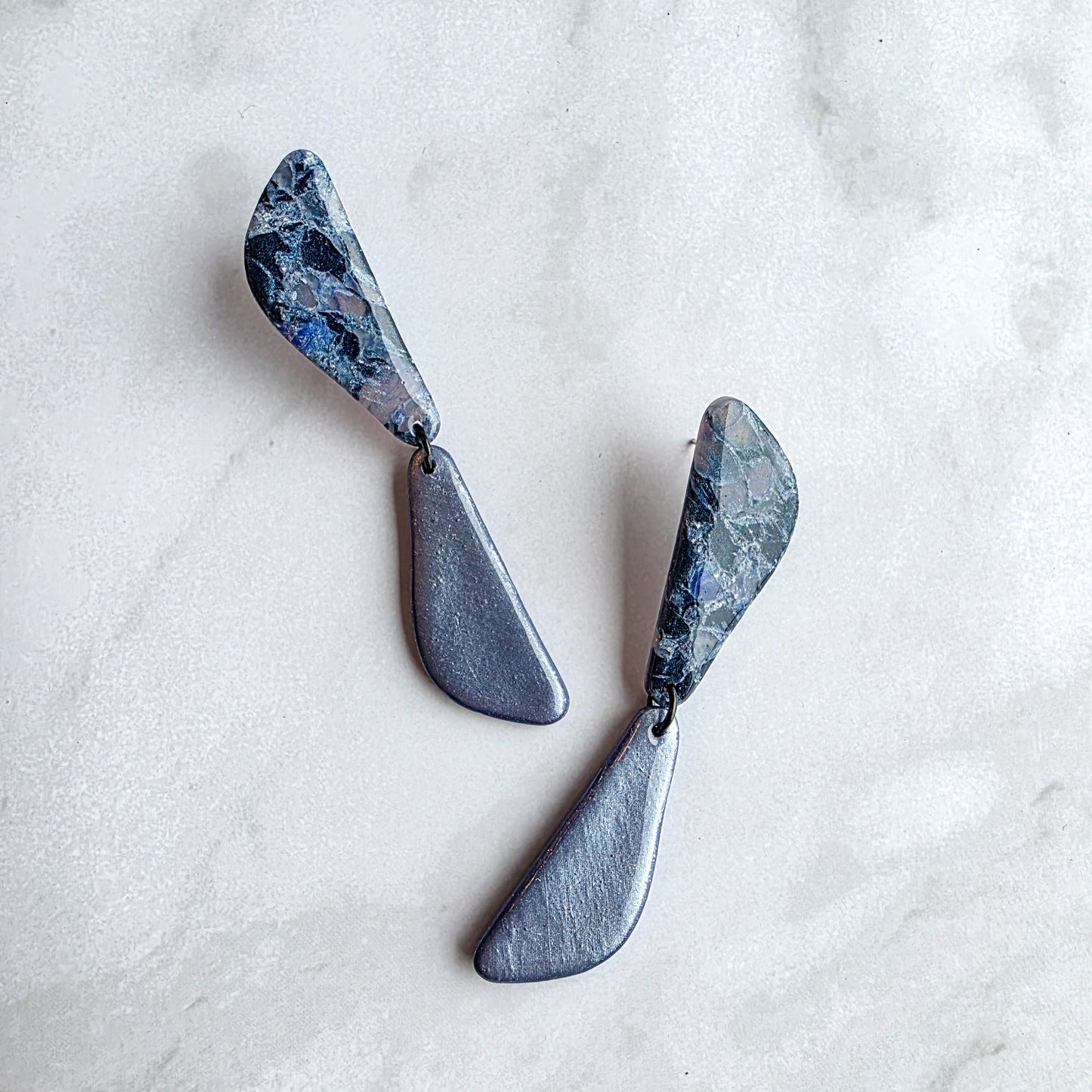 lange koel blauwe oorbellen op wit grijs marmeren blad