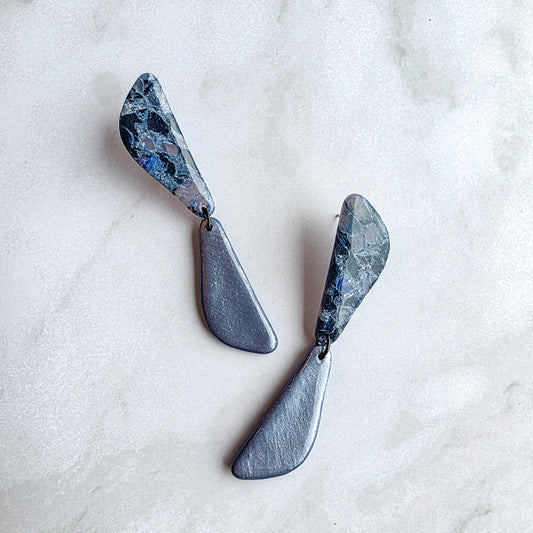 lange koel blauwe oorbellen op wit grijs marmeren blad