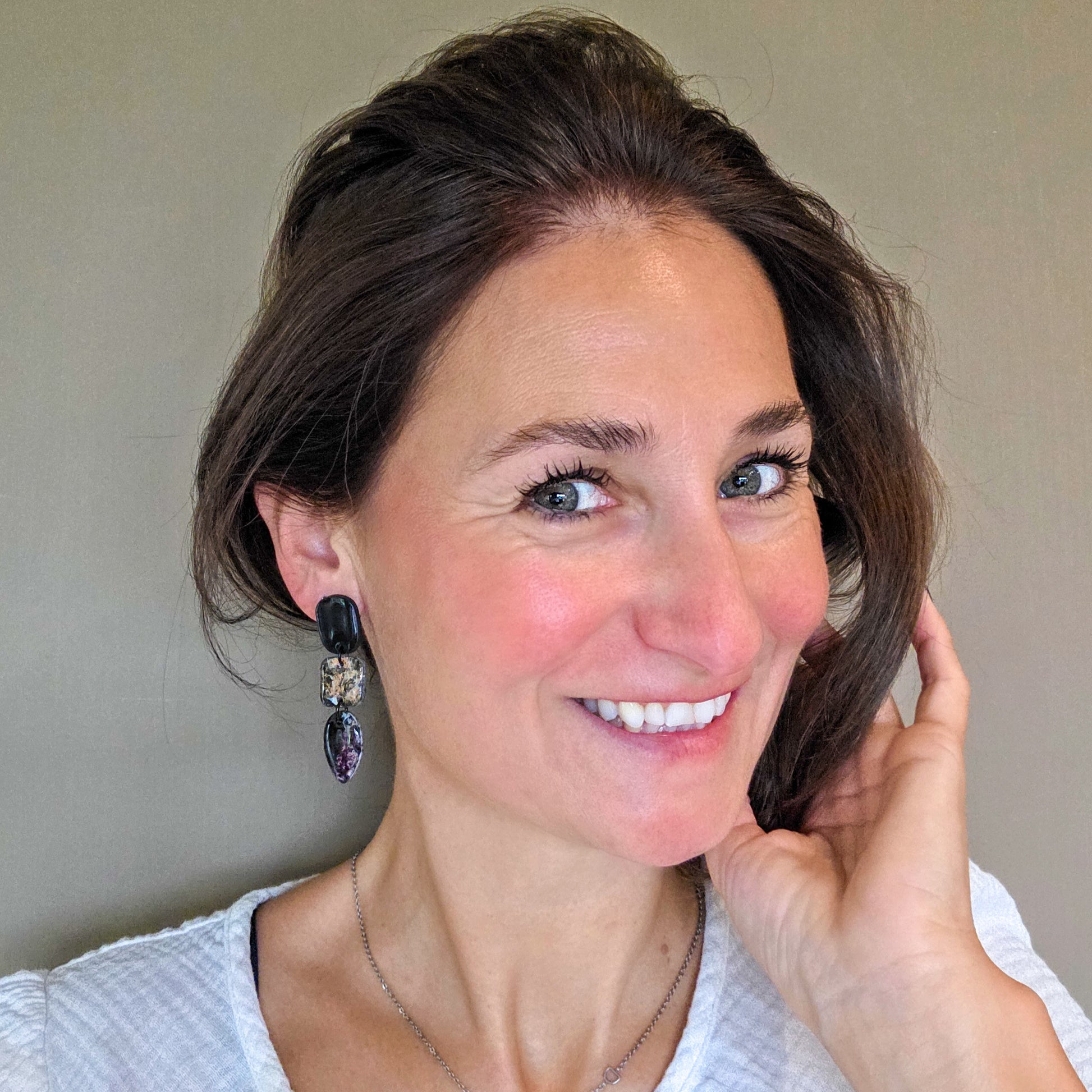 vrouw draagt lange zwarte oorbellen met druppelvorm in geschilderde metallic kleuren