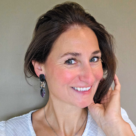 vrouw draagt lange zwarte oorbellen met druppelvorm in geschilderde metallic kleuren