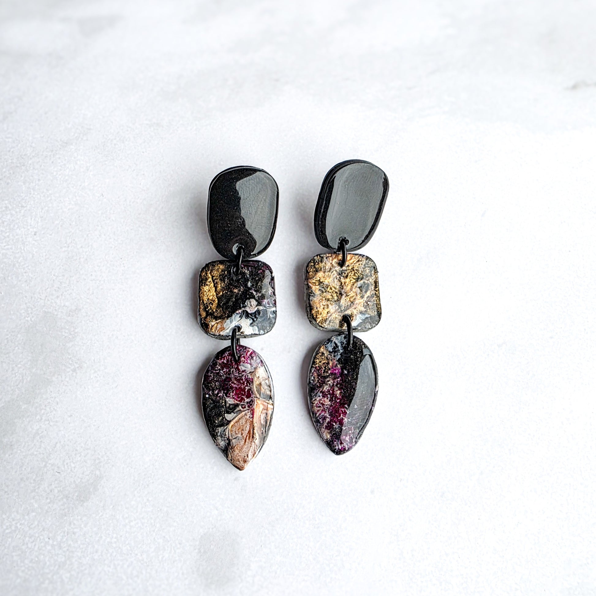 druppelvormige zwarte oorbellen met goud geschilderde kleur op wit grijs marmeren blad