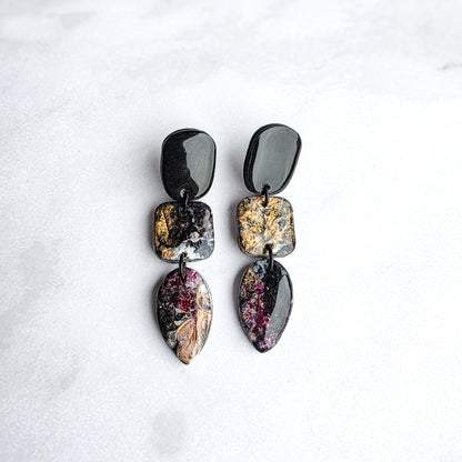 druppelvormige zwarte oorbellen met goud geschilderde kleur op wit grijs marmeren blad