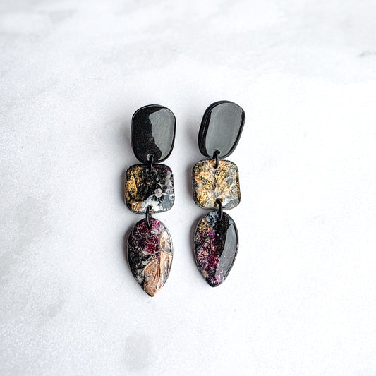 druppelvormige zwarte oorbellen met goud geschilderde kleur op wit grijs marmeren blad