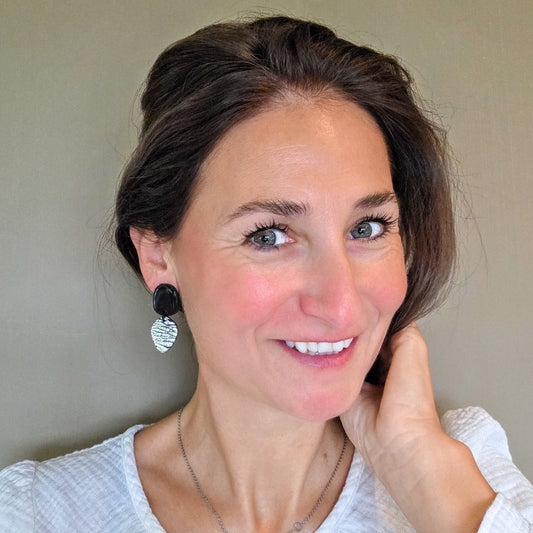 vrouw draagt korte zwarte oorbellen met druppelvorm in zilver metallic